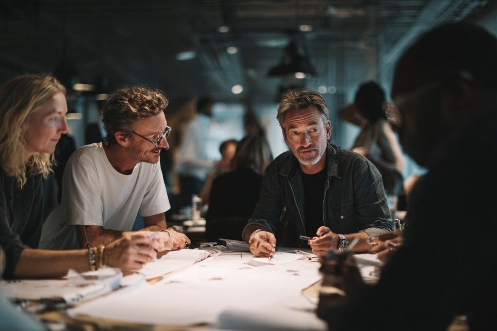 Un groupe d'artistes variés partageant des idées et travaillant sur des croquis autour d'une table ronde.