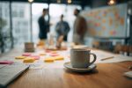Une équipe échangeant des idées lors d'une séance de brainstorming avec des documents financiers et des boissons chaudes sur la table