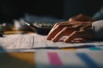 Mains triant les feuilles de calcul et rapports pour une gestion rigoureuse du déficit budgétaire.
